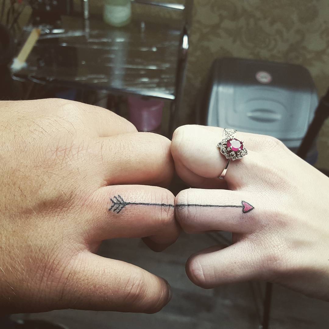 Symbolic arrow tattoos on couple's fingers