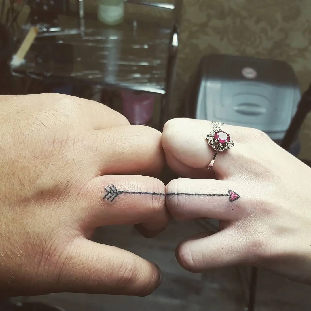 Symbolic arrow tattoos on couple's fingers