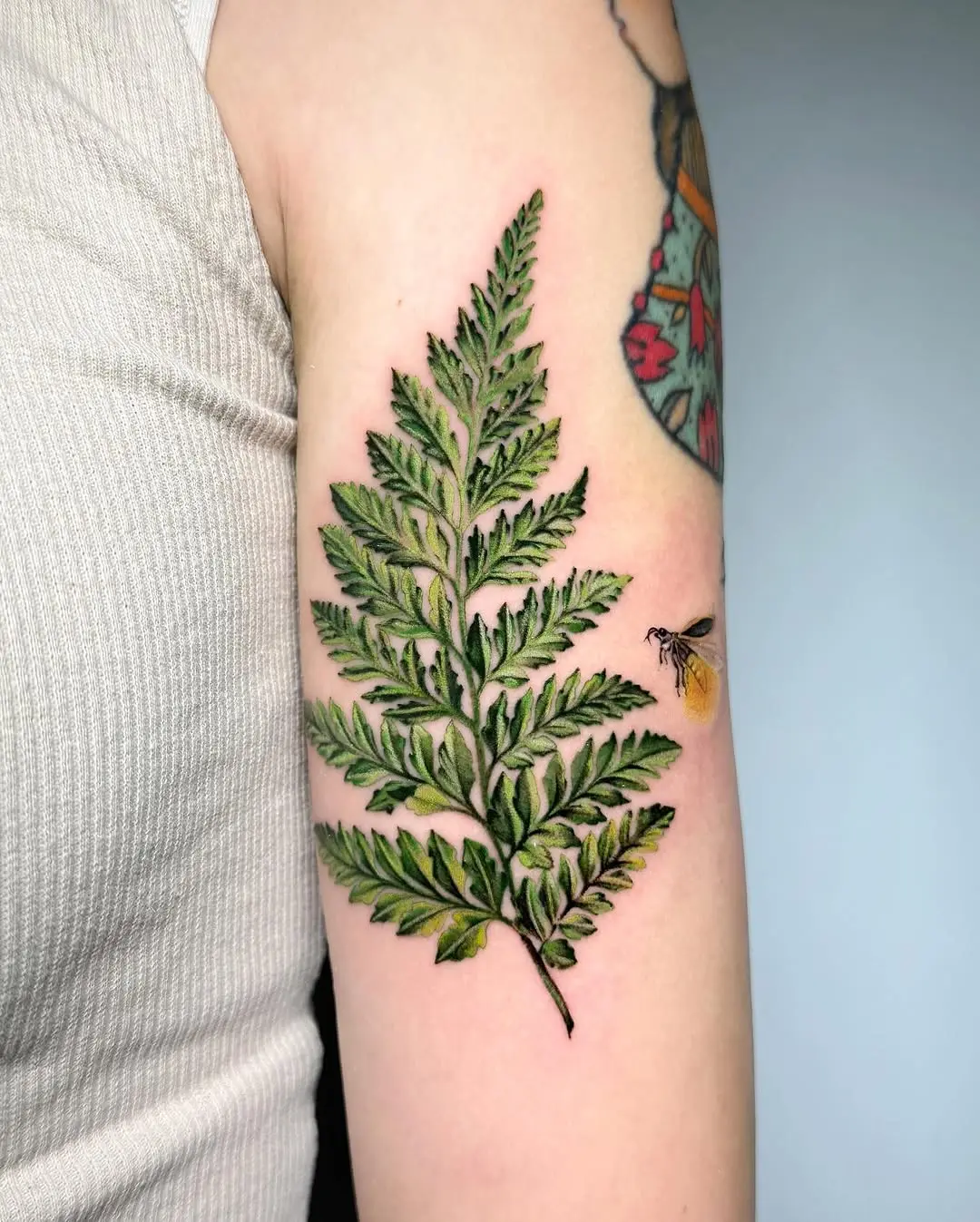 Nature-inspired firefly tattoo with fern design
