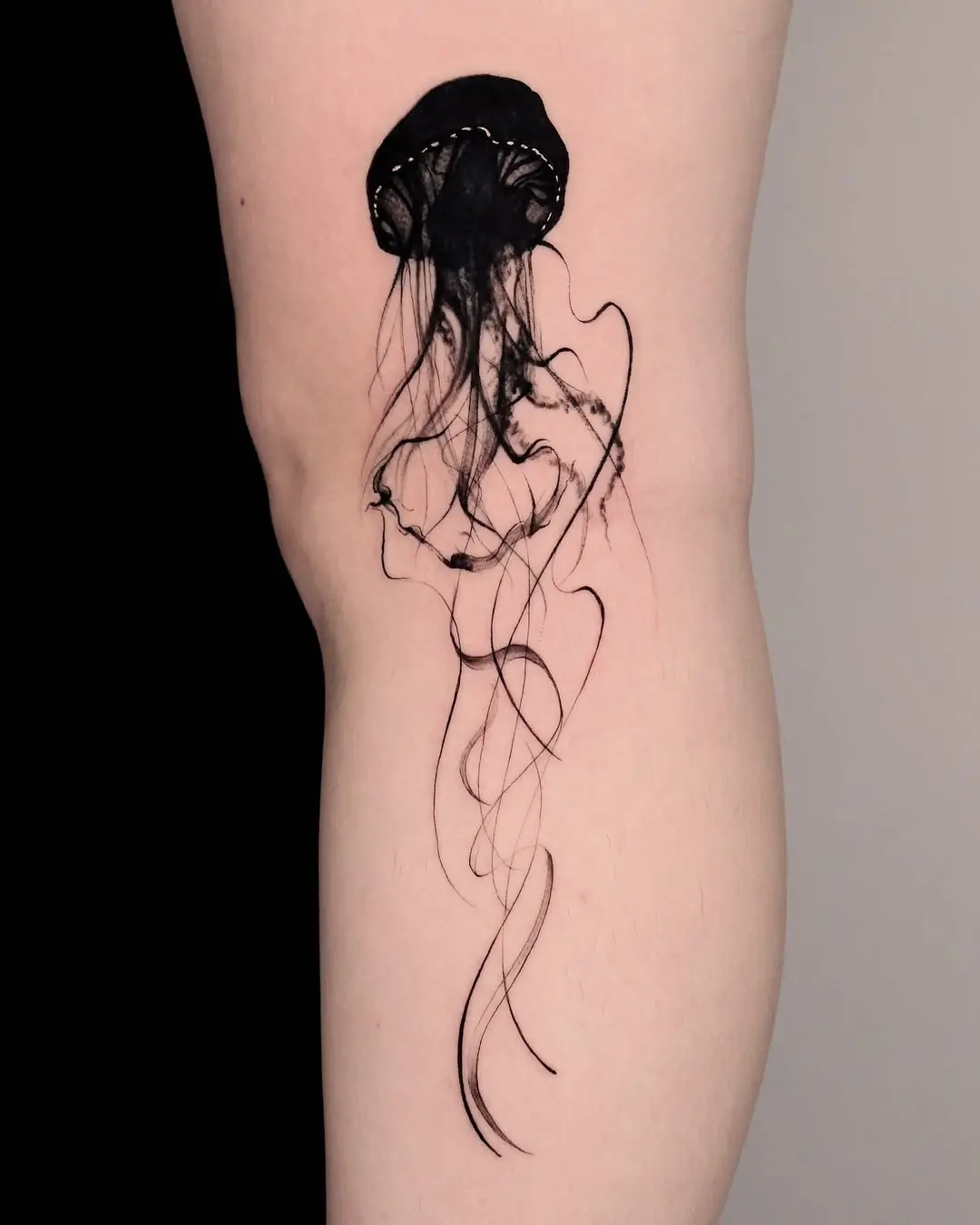 Elegant black jellyfish tattoo on the thigh
