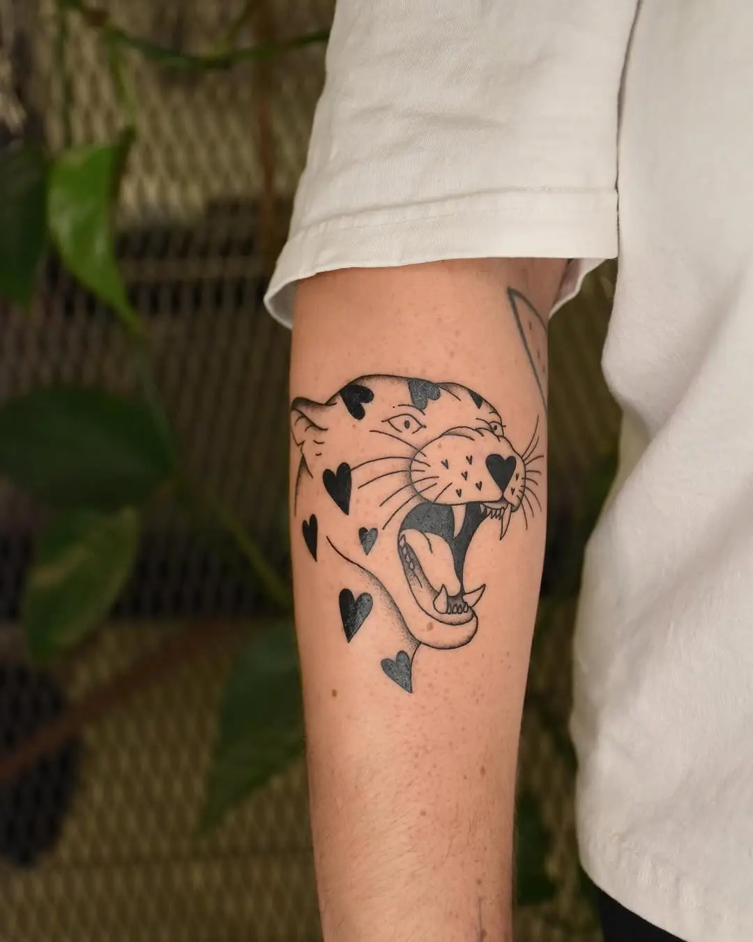 Striking black leopard tattoo with heart accents