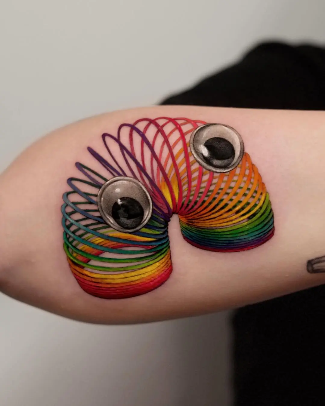 Playful 3D slinky tattoo with googly eyes