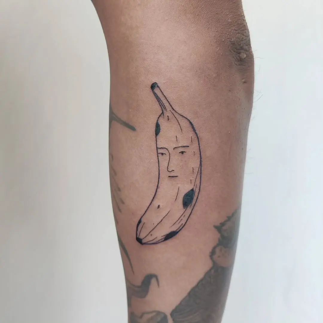 Whimsical banana tattoo with a quirky face