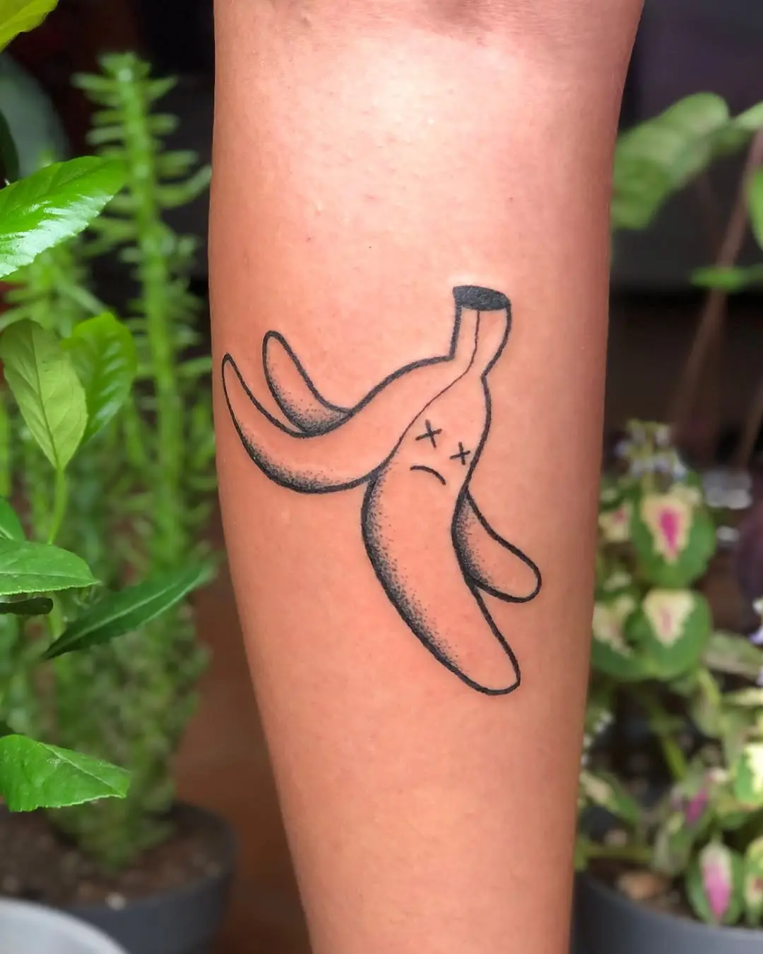 Quirky banana tattoo with a sad expression