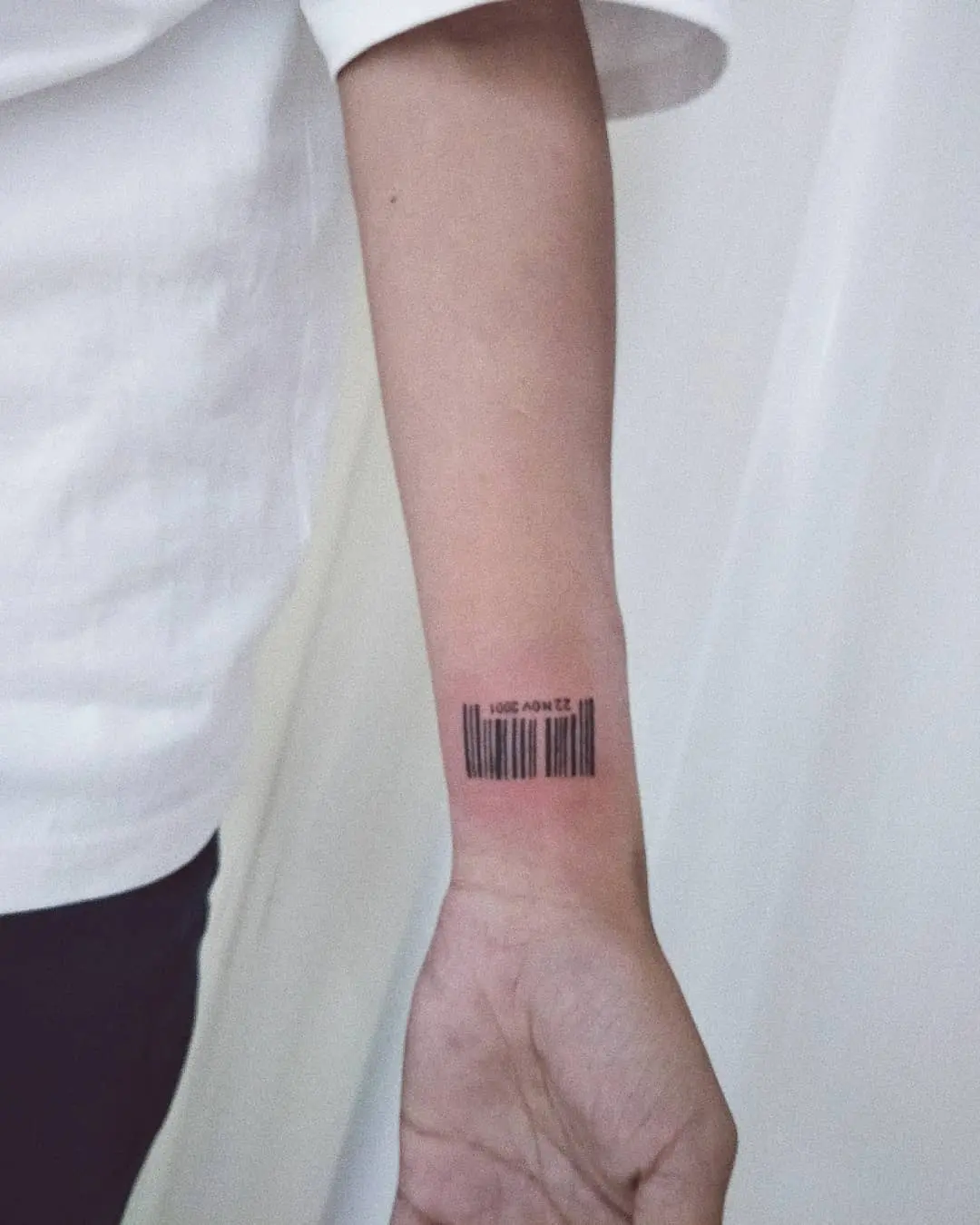 Minimalist barcode tattoo on the forearm