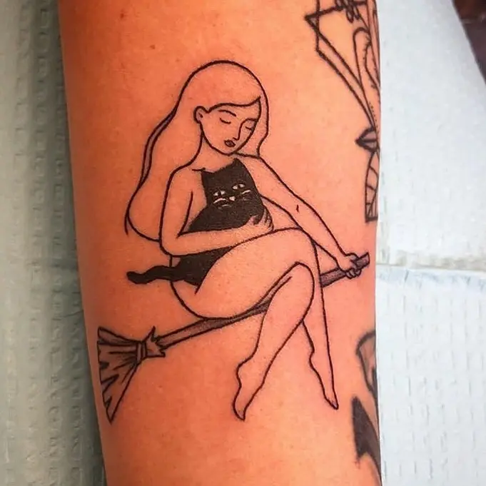 Charming cat tattoo on a witch's broomstick