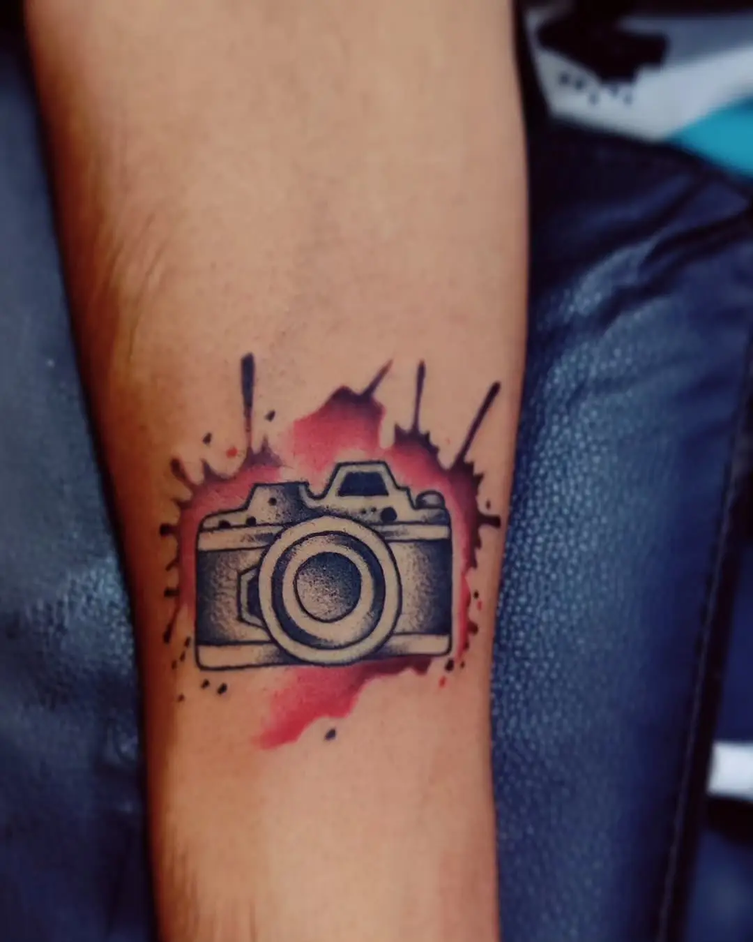 Artistic camera tattoo with vibrant ink splashes