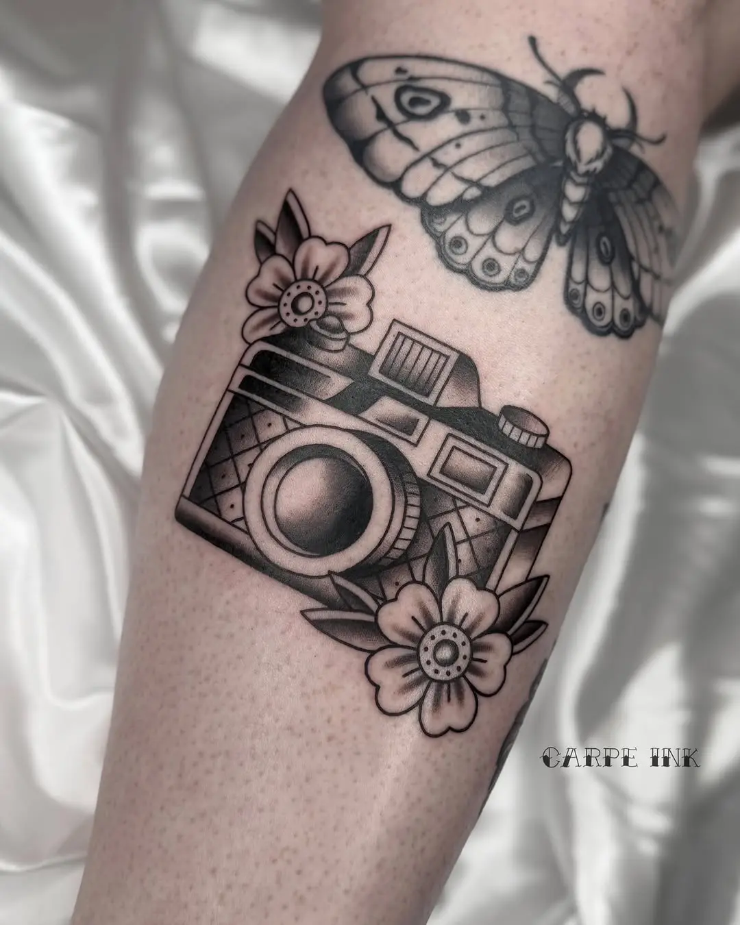 Artistic camera tattoo surrounded by floral motifs