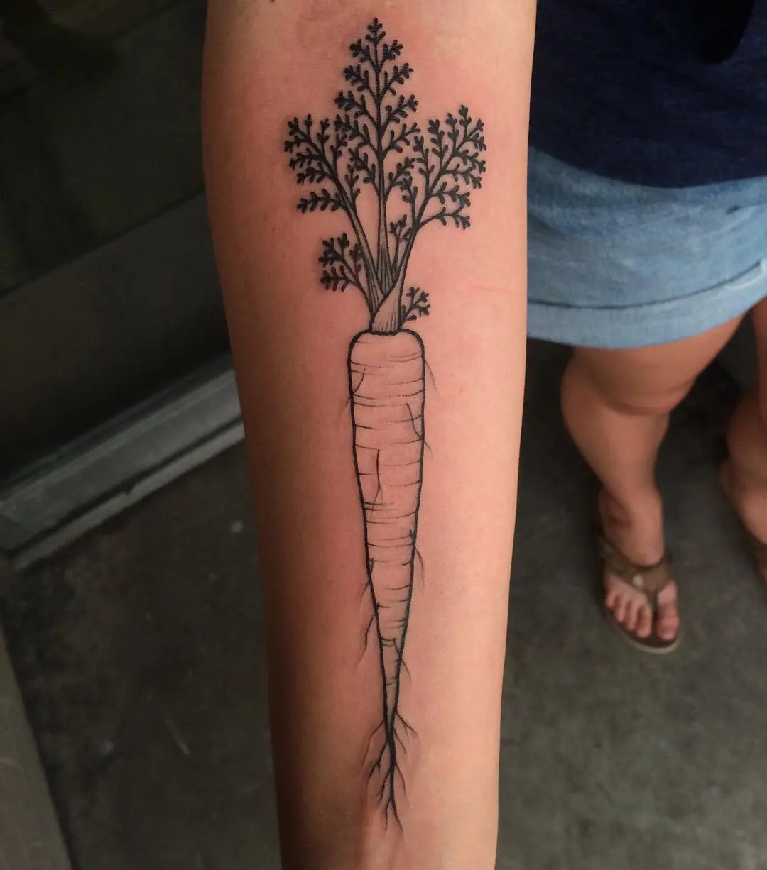 Elegant carrot tattoo on a forearm
