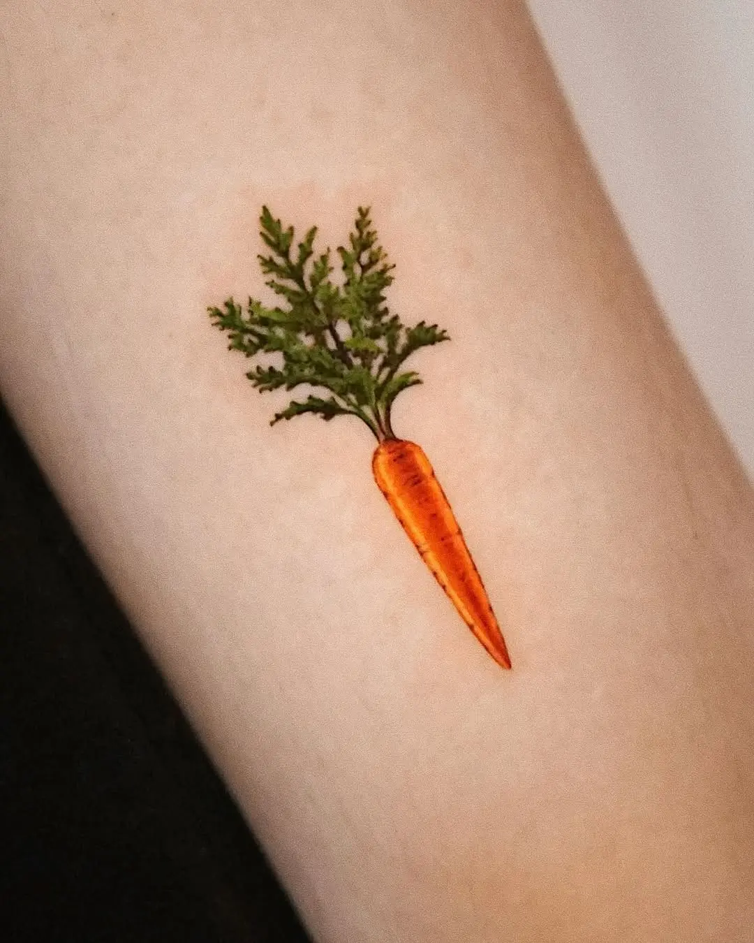 Colorful carrot tattoo with leafy details.