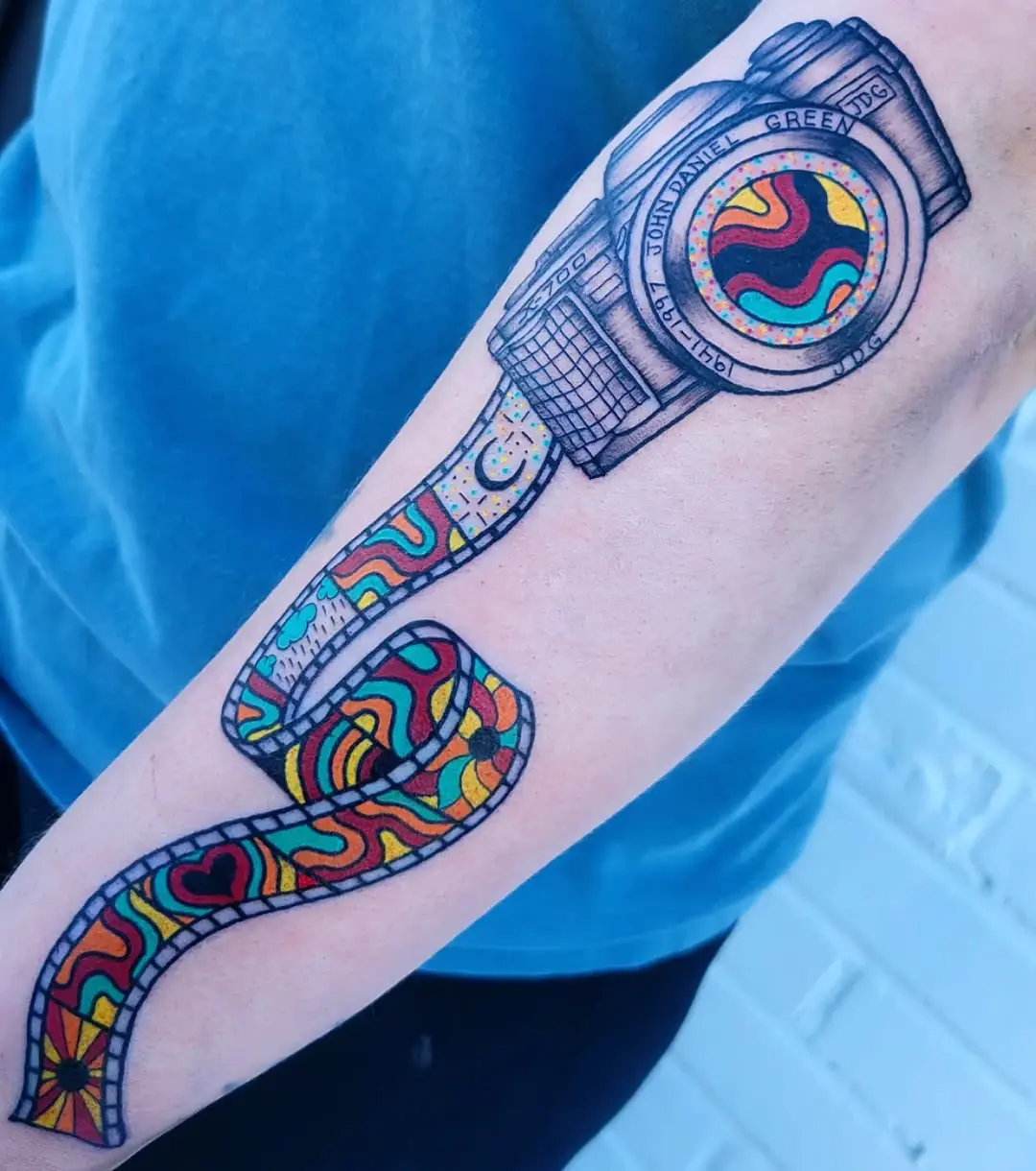 Vibrant camera tattoo with film strip design.