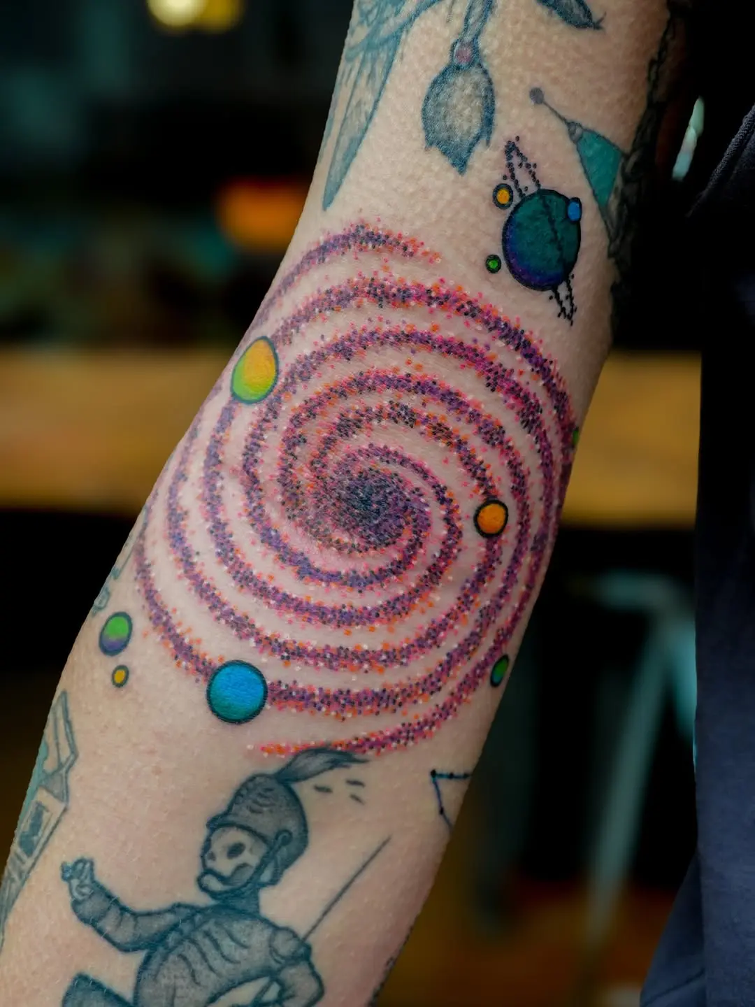 Colorful spiral galaxy tattoo on forearm