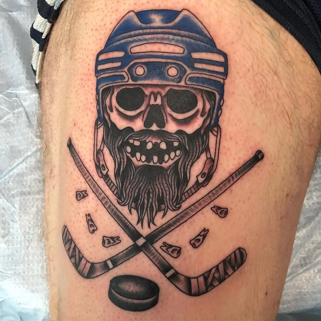 Bold hockey skull tattoo with crossed sticks