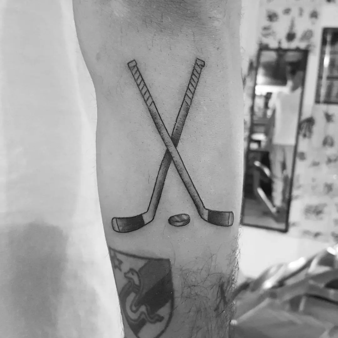 Stylish crossed sticks tattoo for hockey lovers