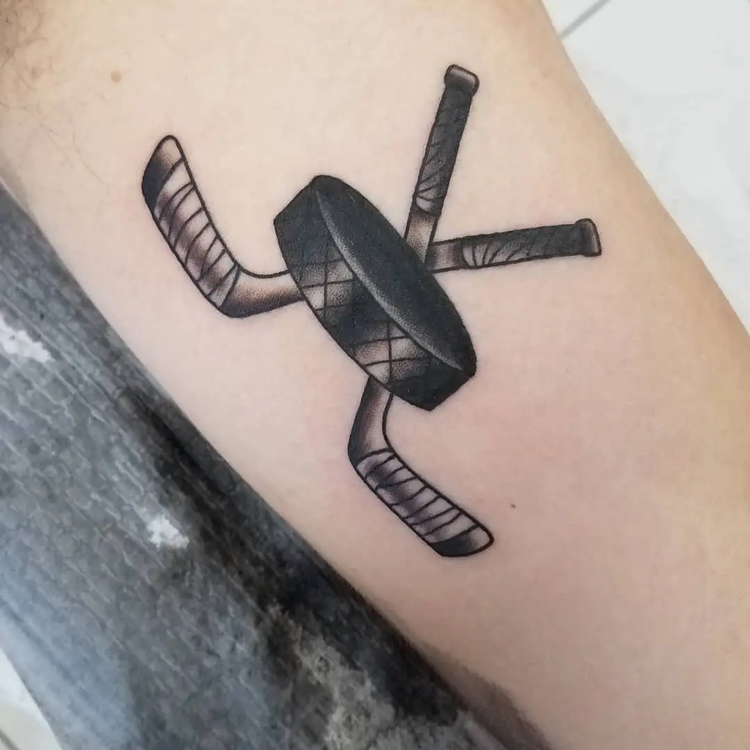 Stylish hockey tattoo showcasing sticks and puck