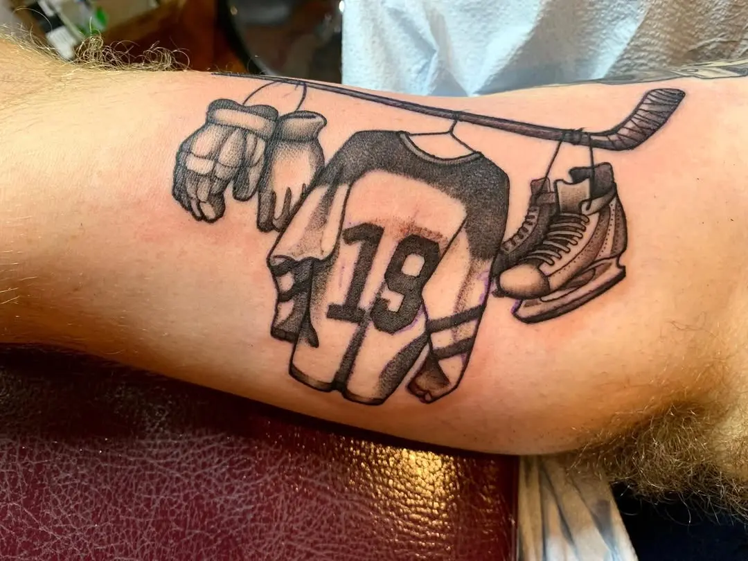 Symbolic hockey gear tattoo showcasing passion.