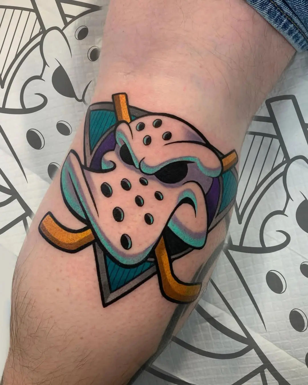 Bold hockey mask tattoo with crossed sticks