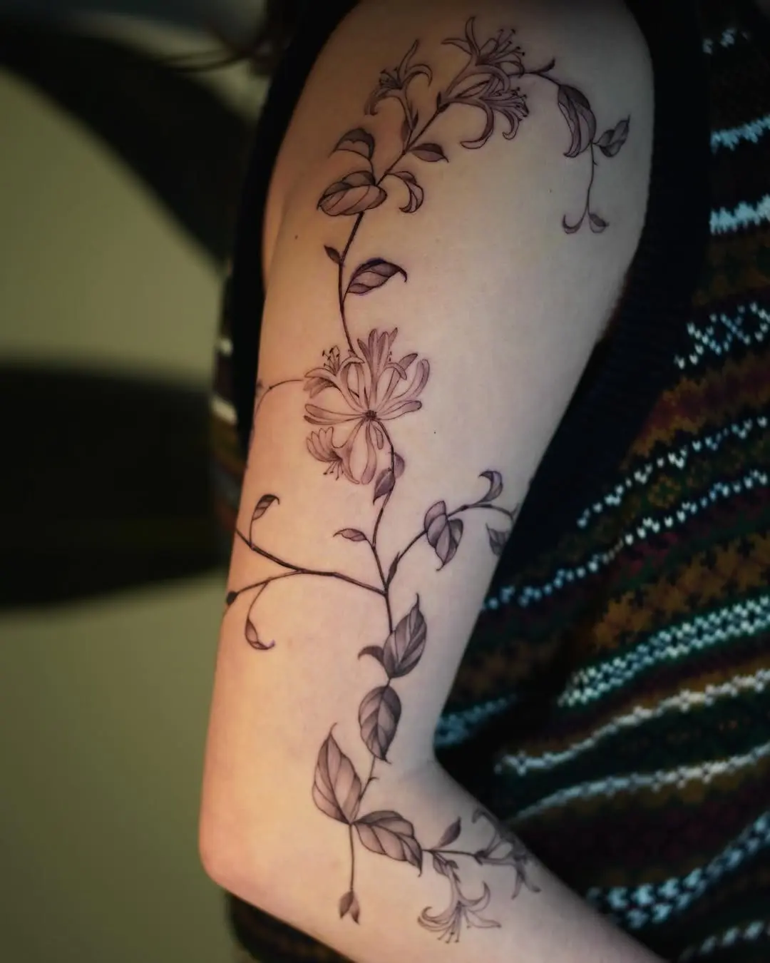 Delicate honeysuckle tattoo spiraling along arm