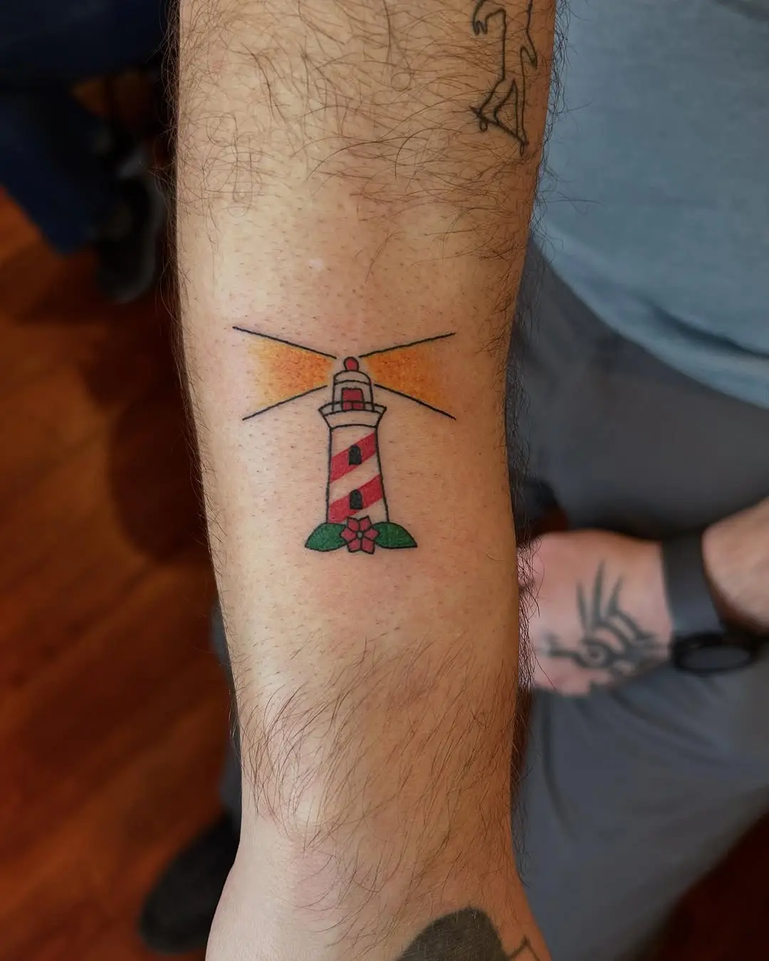 Colorful lighthouse tattoo with floral accents