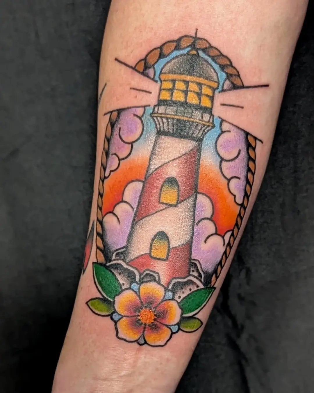 Vibrant lighthouse tattoo with floral accents