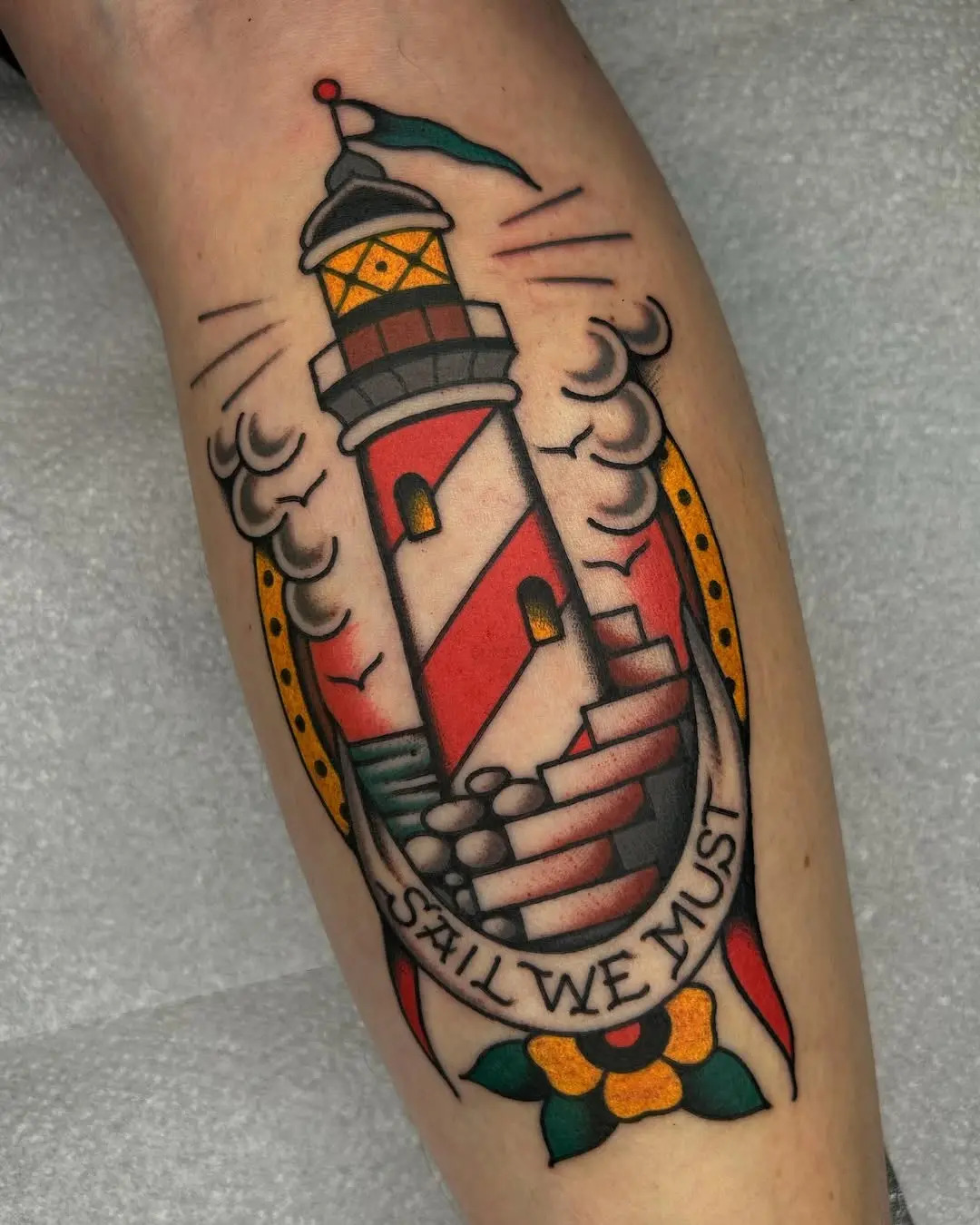 Vibrant lighthouse tattoo with a motivational message
