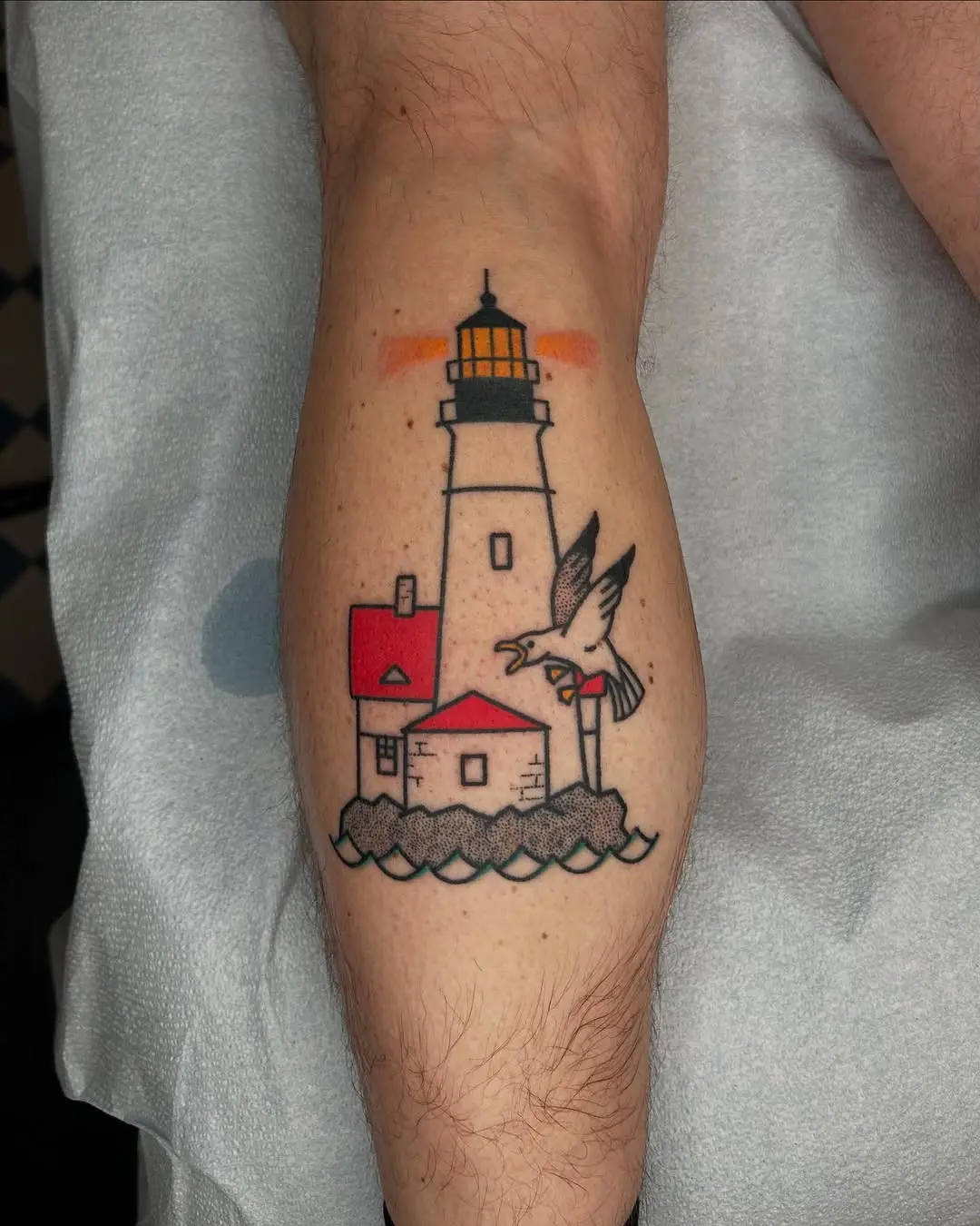 Vibrant lighthouse tattoo with a seagull motif