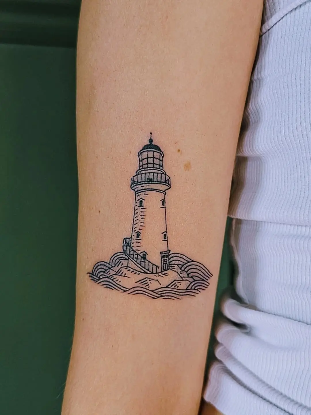 Minimalist lighthouse tattoo showcasing gentle waves