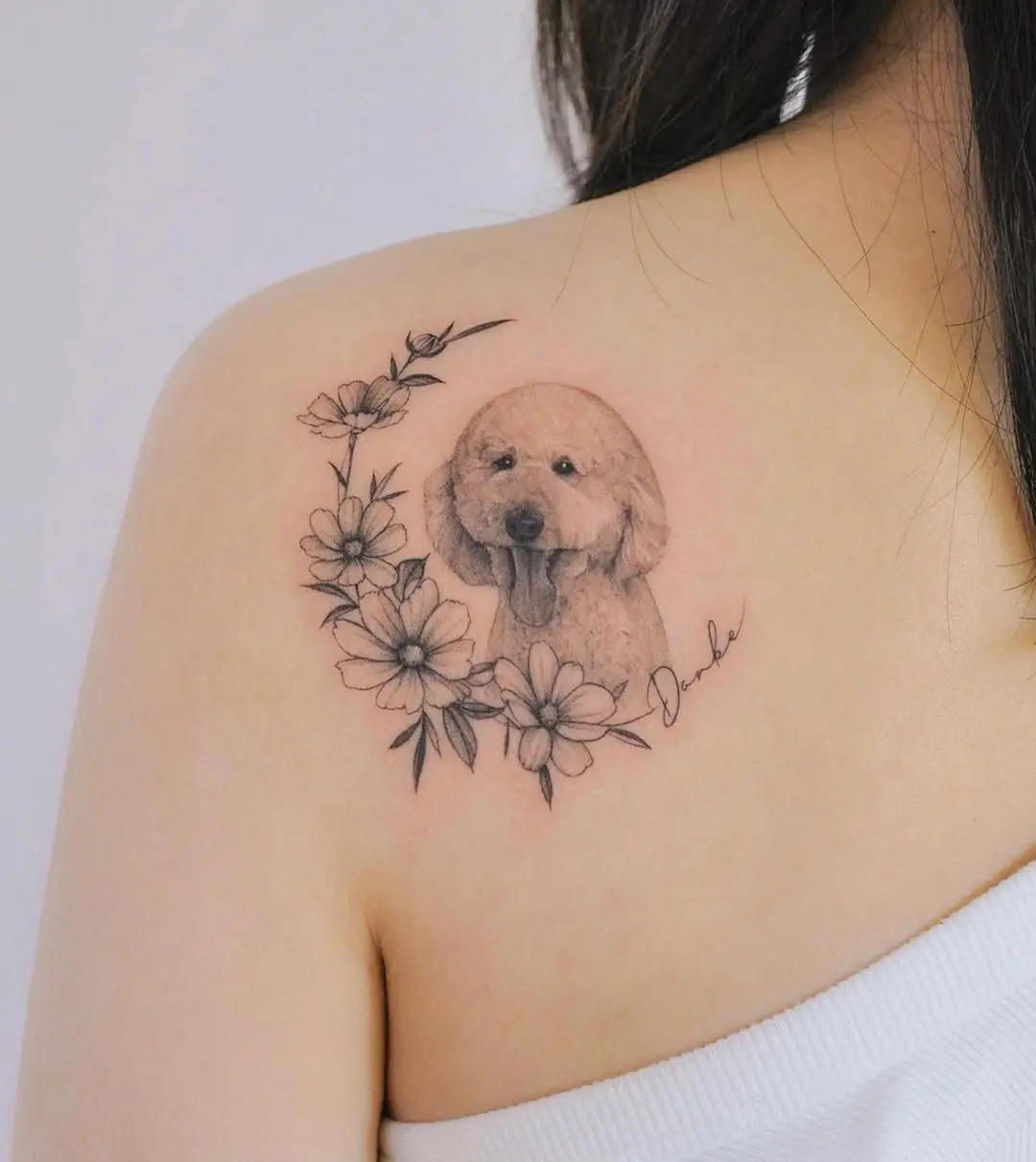 Charming poodle tattoo surrounded by floral accents