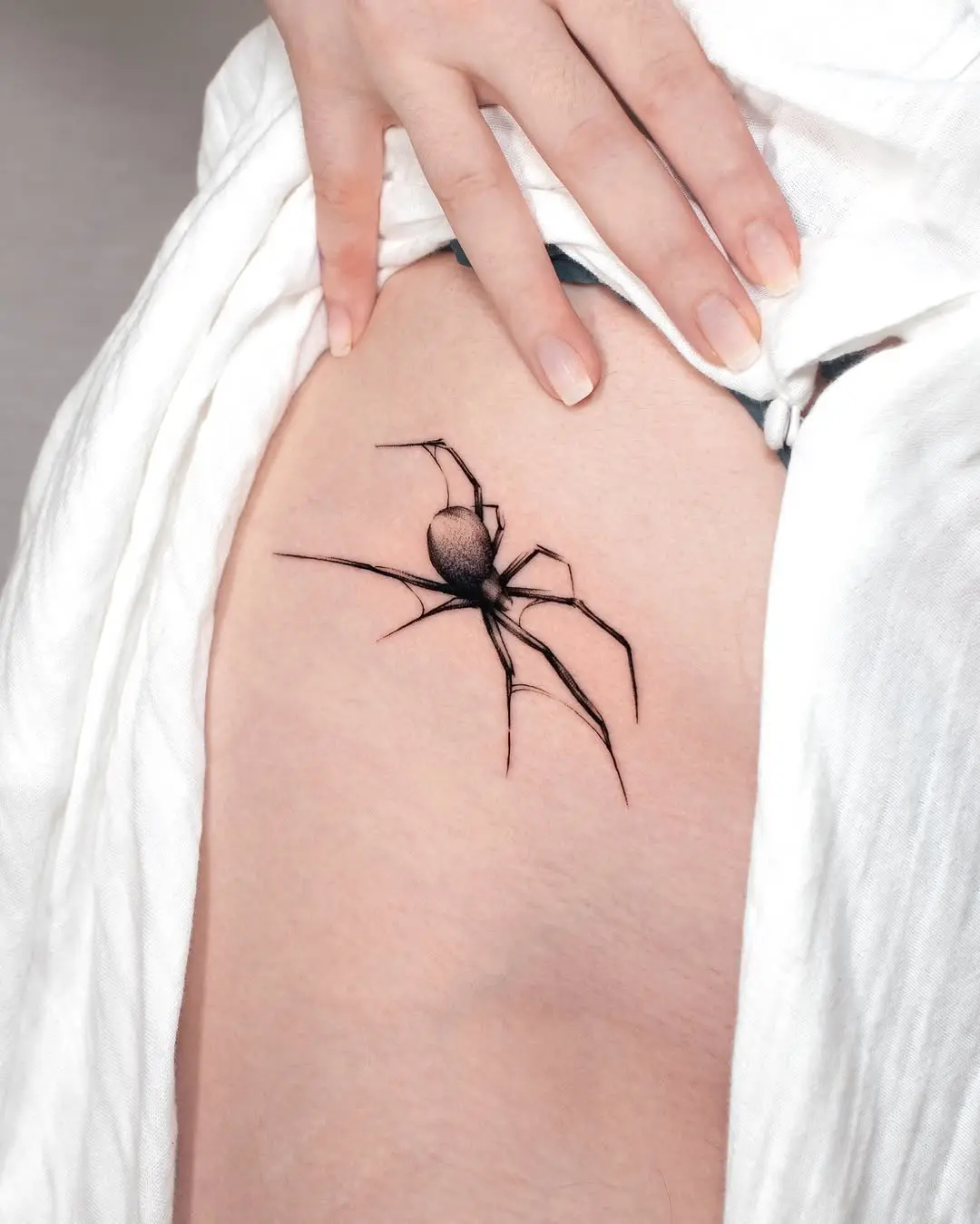 Striking black spider tattoo on thigh area
