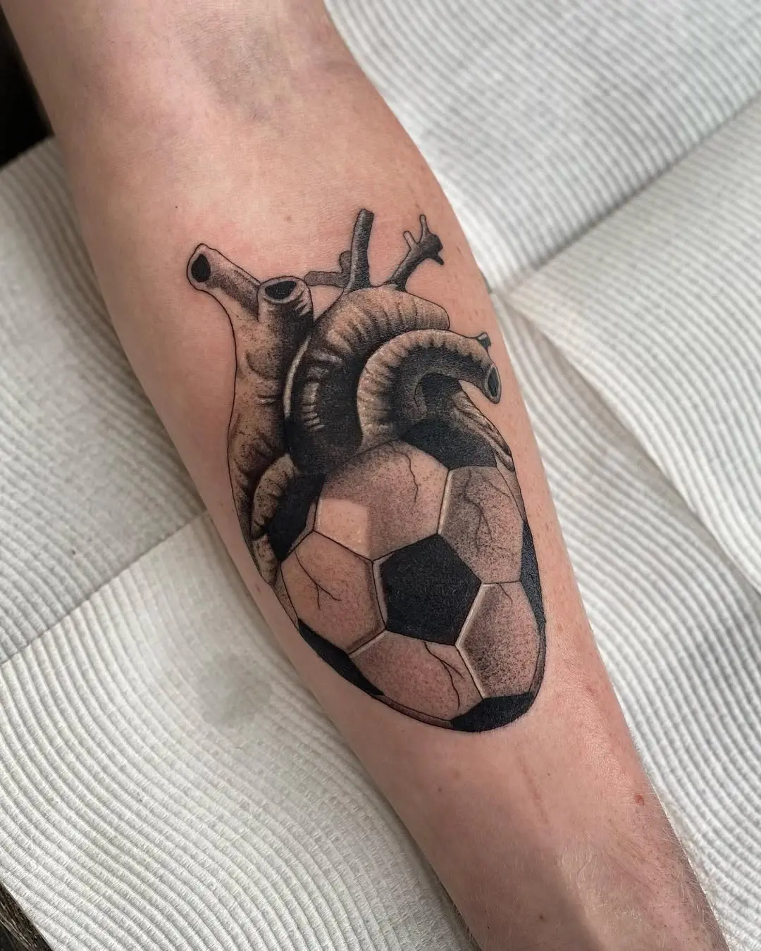 Heart and soccer ball intertwined in tattoo art