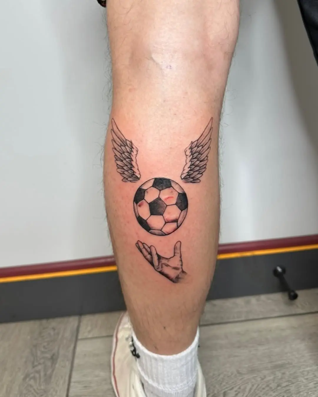 Winged Soccer Ball Tattoo with Hand Gesture