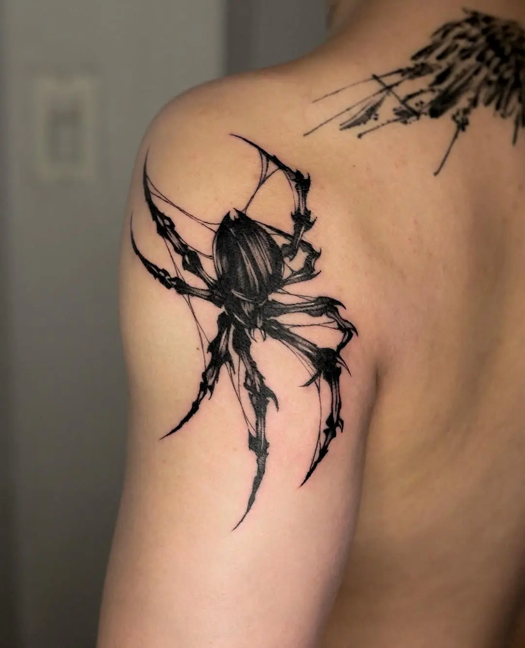 Intricate black spider tattoo on shoulder