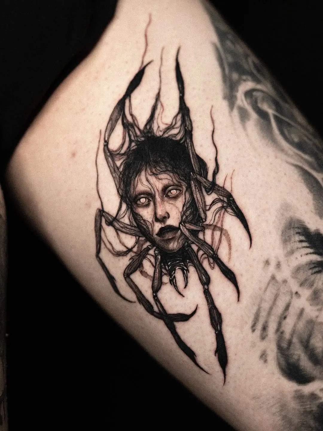 Haunting face within a spider tattoo design