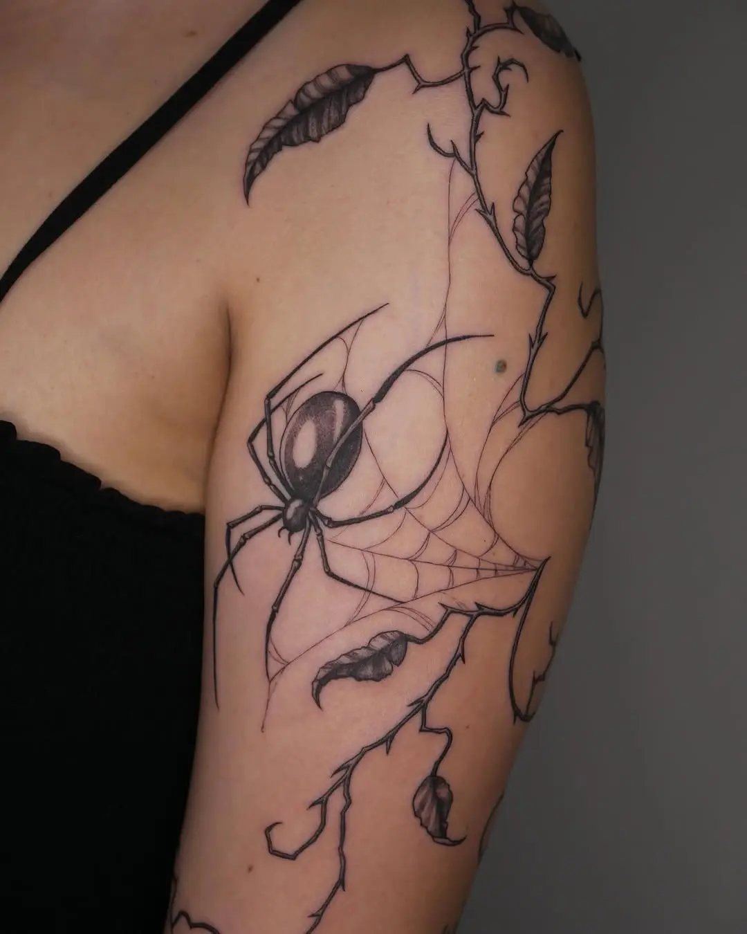 Intricate spider web tattoo with botanical elements