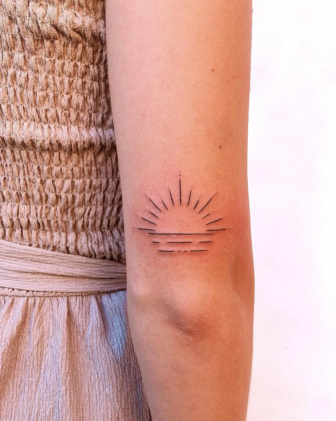 Elegant minimalist sunrise tattoo on the arm