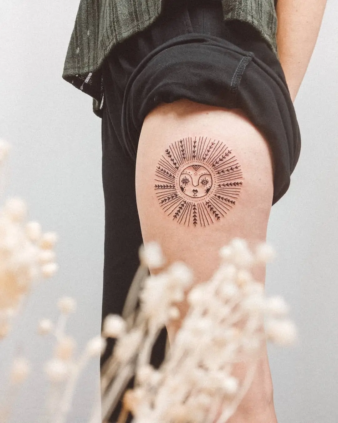 Vibrant sunrise tattoo on thigh accentuated