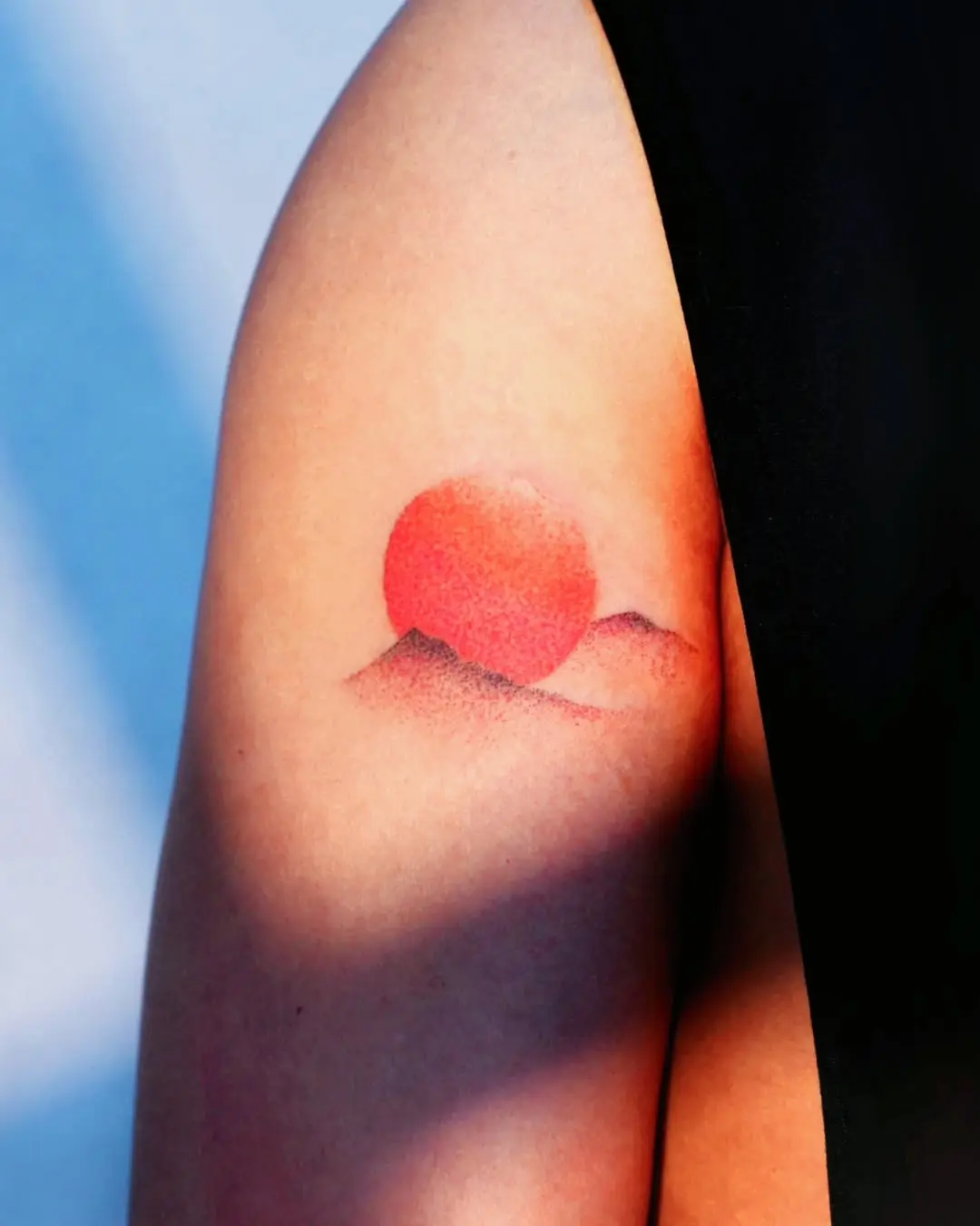 Vibrant sunrise tattoo with soft mountain silhouettes
