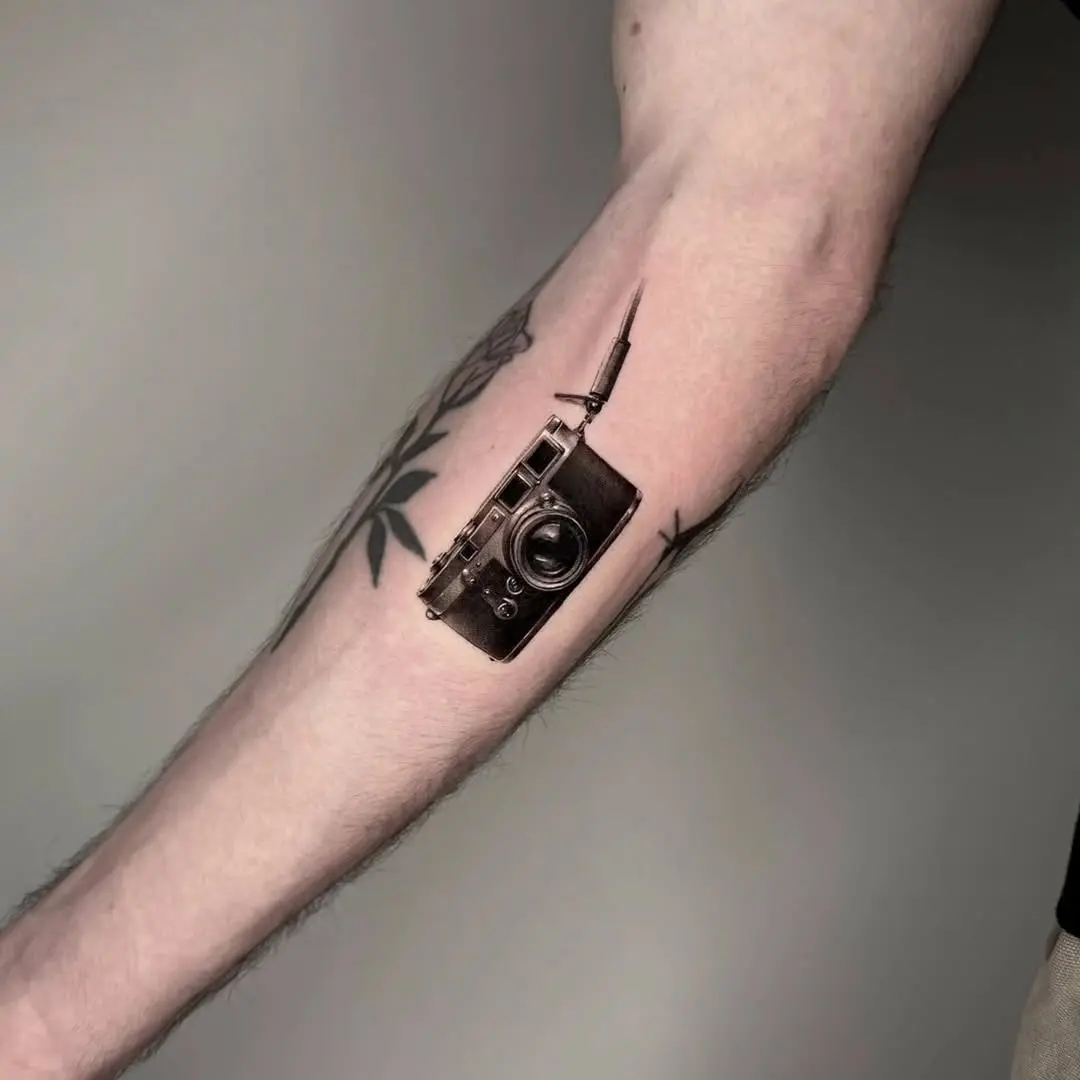 Realistic vintage camera tattoo on forearm