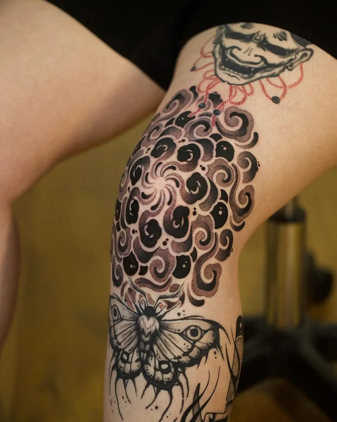 Flowing cloud and moth tattoo on leg