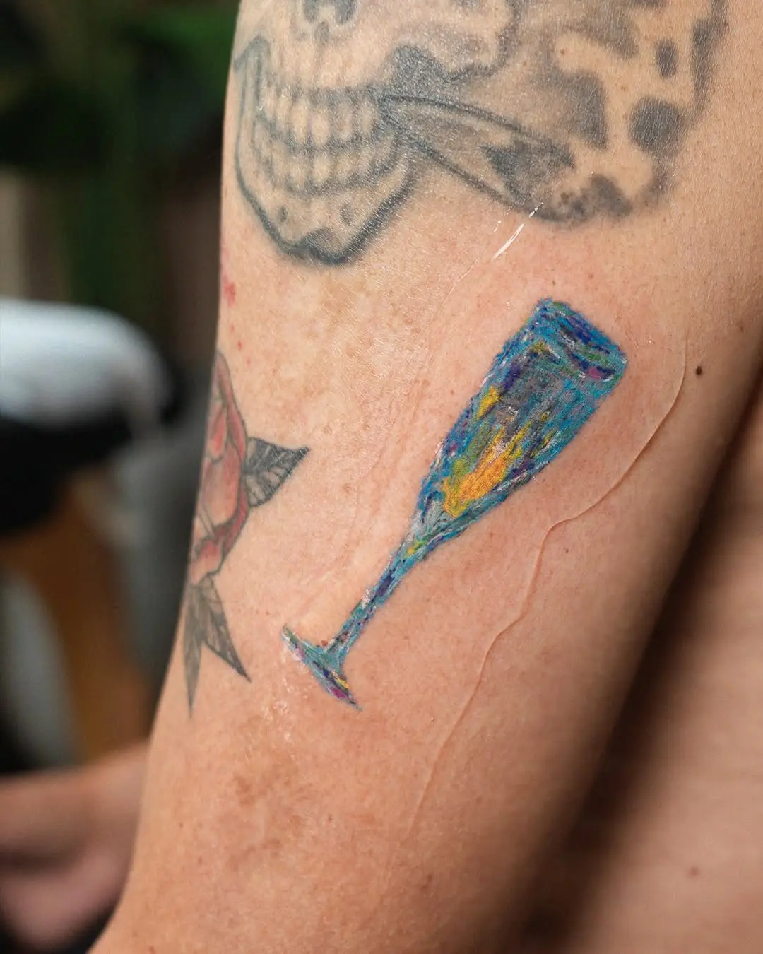 Artful champagne tattoo on a vibrant arm