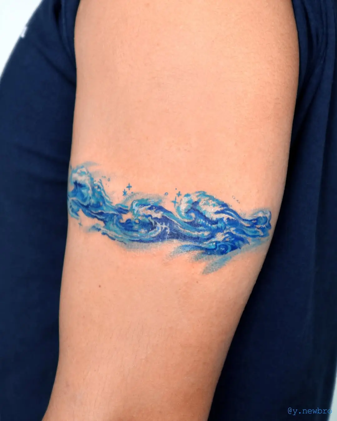 Vibrant ocean wave tattoo on upper arm