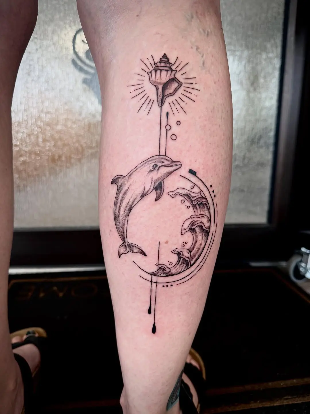 Intricate dolphin and wave tattoo design