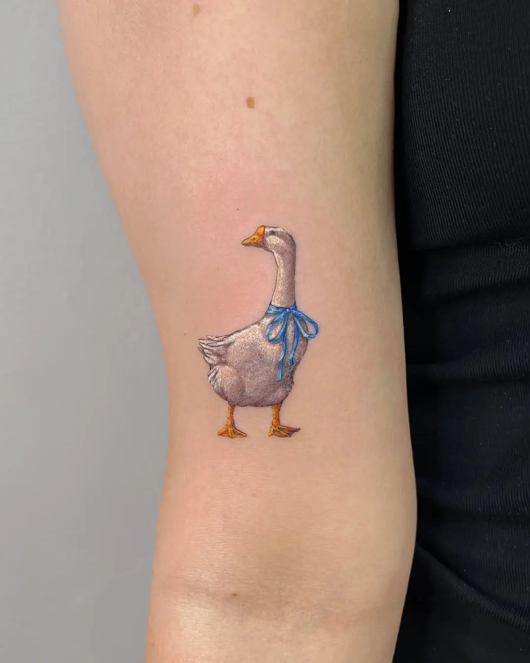 Charming duck tattoo with a blue ribbon