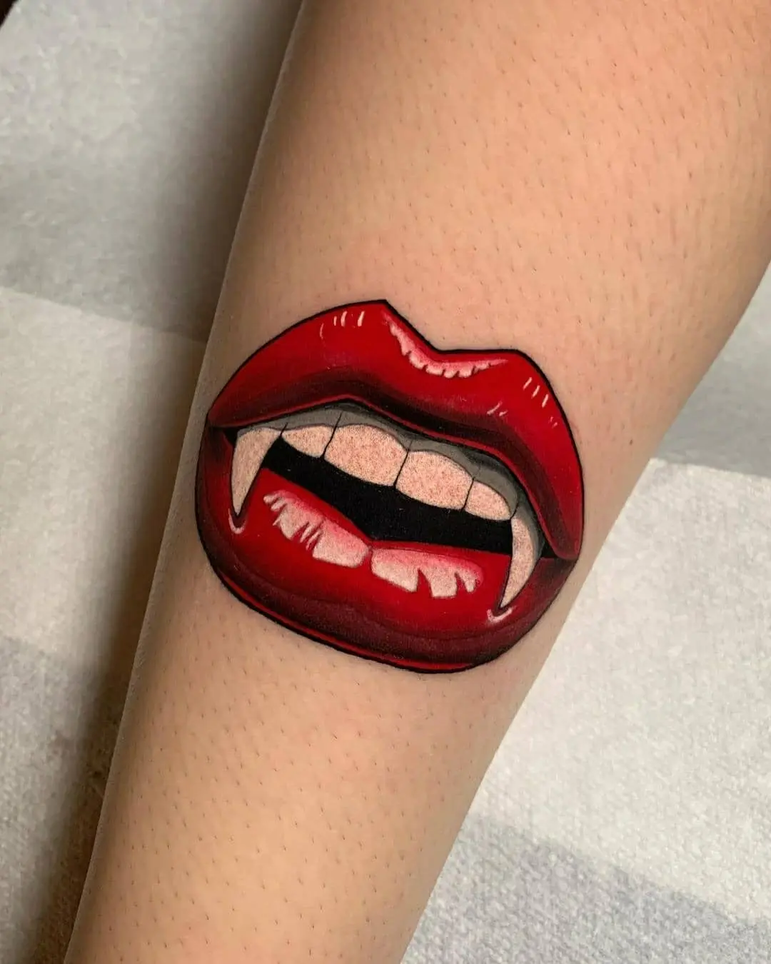 Bold lip tattoo with vampire fangs design