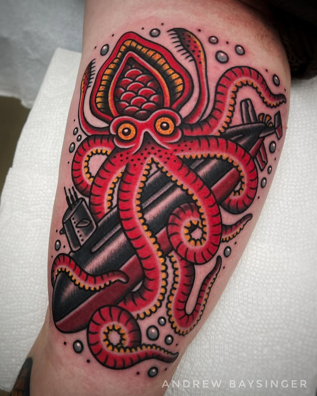 Bold octopus wraps around a submarine tattoo.