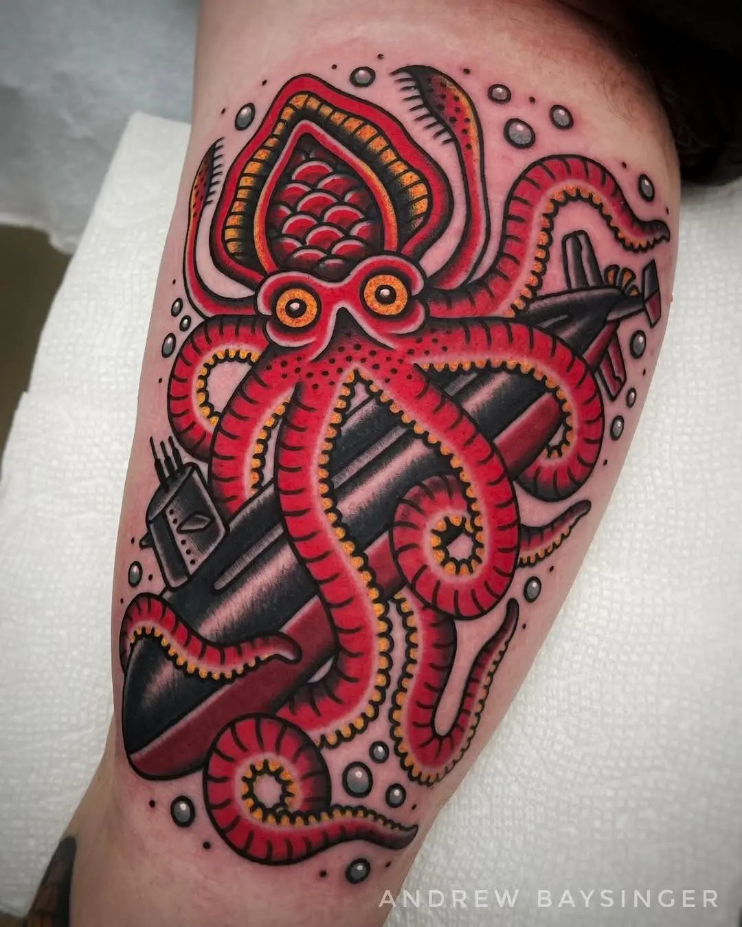 Bold octopus wraps around a submarine tattoo.