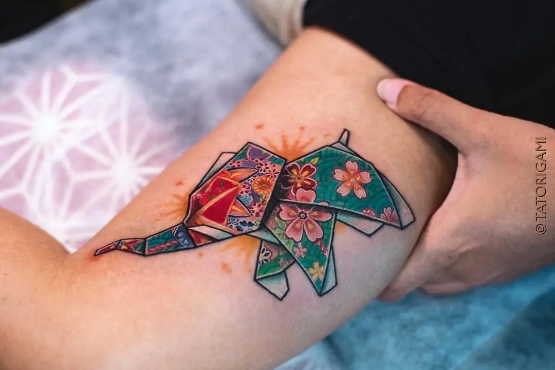 Colorful origami elephant tattoo with floral design