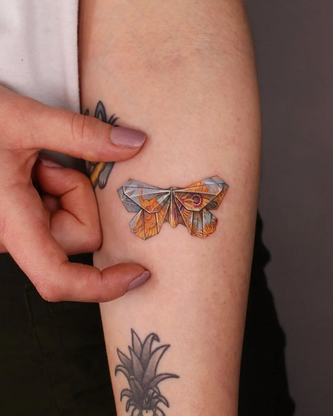 Colorful origami moth tattoo on the arm
