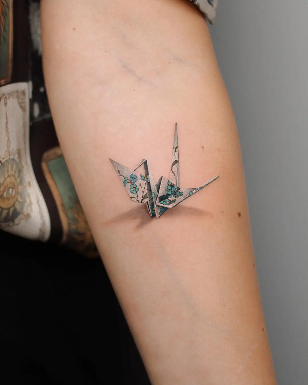 Elegant origami crane tattoo with floral details