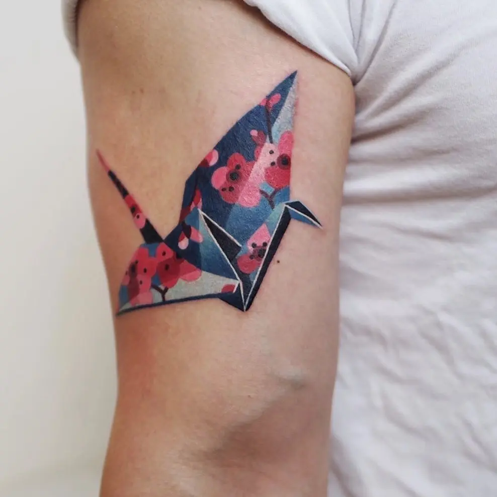Colorful origami crane tattoo with floral elements